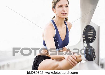 Stock Image - Hispanic woman stretching before exercise. Fotosearch