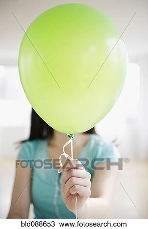 Stock Image - Korean woman holding balloon in front of her face. Fotosearch