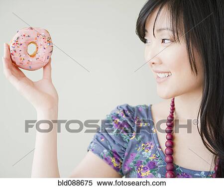 Stock Photography - Korean woman holding donut. Fotosearch