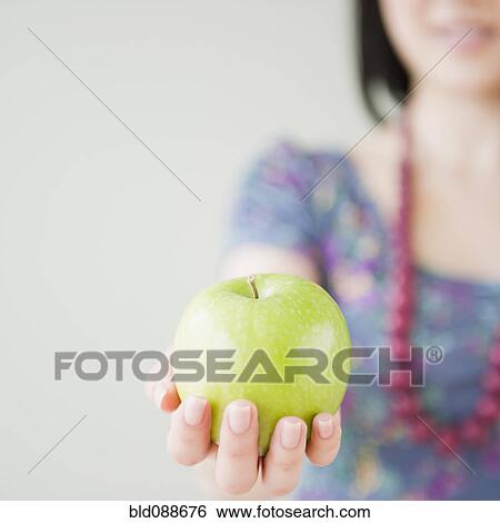 Stock Photograph - Korean woman holding green apple. Fotosearch