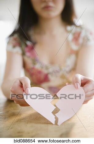 Picture - Korean woman holding torn paper heart. Fotosearch