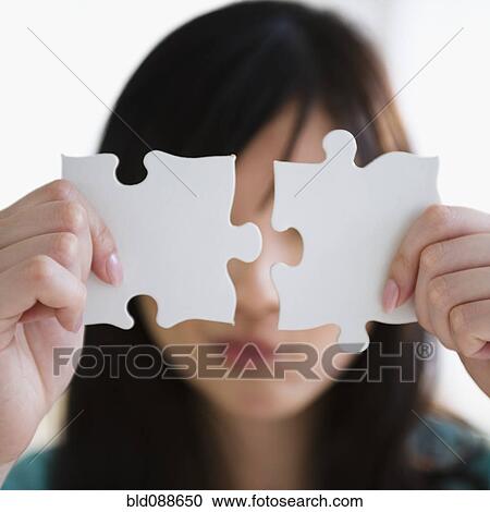 Stock Image - Korean woman holding two puzzle pieces. Fotosearch