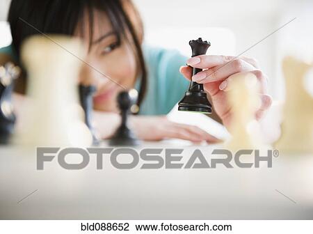 Stock Image - Korean woman playing chess. Fotosearch