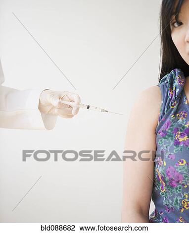 Stock Image - Korean woman receiving injection. Fotosearch