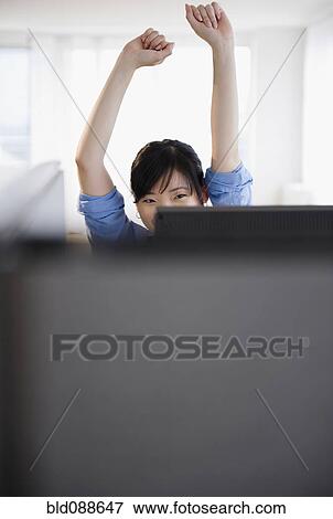 Stock Photo - Korean woman stretching at desk. Fotosearch