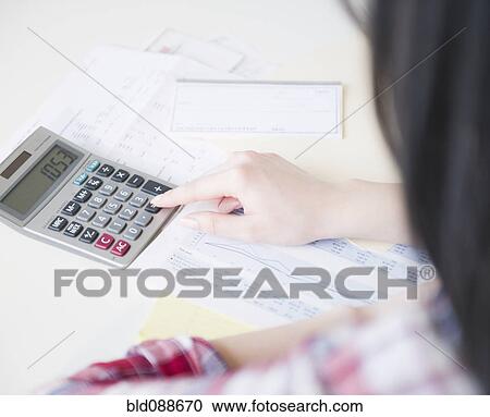 Stock Image - Korean woman using calculator. Fotosearch