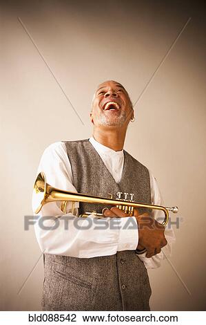 Stock Image - Laughing musician holding trumpet. Fotosearch