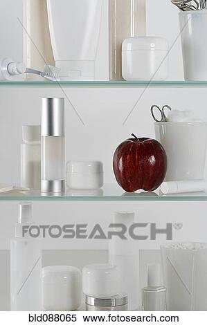 Stock Photography - Medicine cabinet full of skincare products and a red apple. Fotosearch