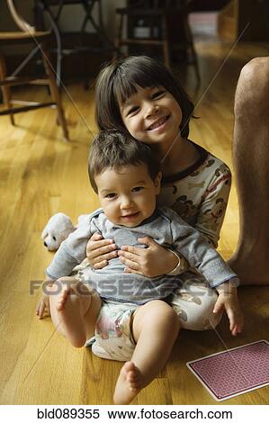 Stock Photography - Mixed race girl holding baby brother. Fotosearch