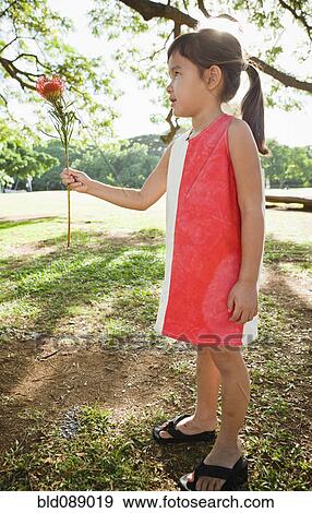 Stock Photo - Mixed race girl holding exotic flower. Fotosearch