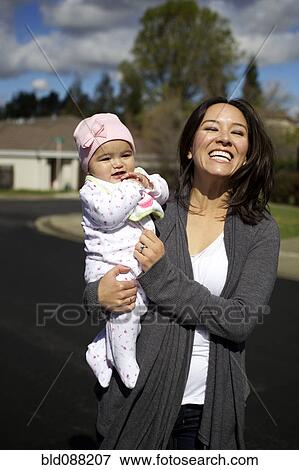 Mixed race mother holding baby girl outdoors View Large Photo Image Stock Photo - Mixed race mother holding baby girl outdoors. Fotosearch