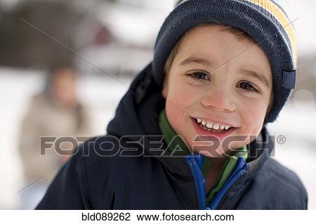 Stock Image - Mixed race smiling boy outdoors in coat and cap. Fotosearch