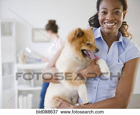 Stock Photo - Mixed race woman holding Pomeranian dog. Fotosearch