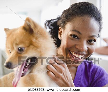 Stock Photo - Mixed race woman petting Pomeranian dog. Fotosearch