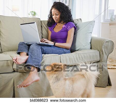 Mixed race woman sitting on sofa using laptop View Large Photo Image Stock Image - Mixed race woman sitting on sofa using laptop. Fotosearch