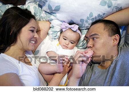 Mother and father laying in bed with baby girl View Large Photo Image Stock Image - Mother and father laying in bed with baby girl. Fotosearch