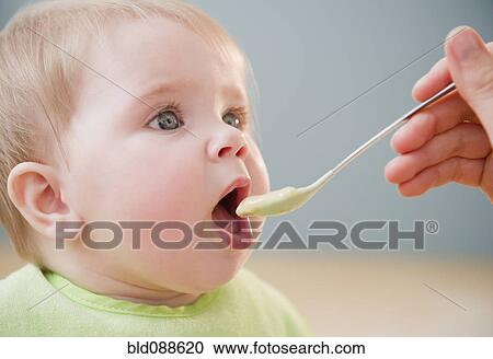 Stock Image - Mother feeding Caucasian baby. Fotosearch