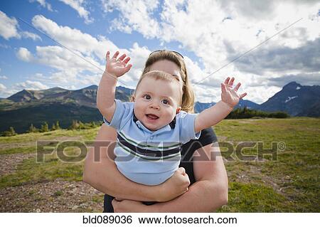 Stock Photograph - Mother holding baby in mountain field. Fotosearch