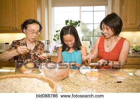 Stock Photograph - Multi-generation Chinese family cooking together. Fotosearch