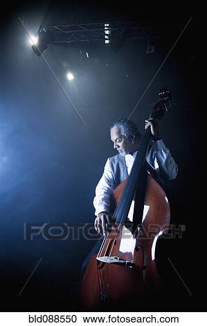 Stock Image - Musician playing double bass on stage. Fotosearch