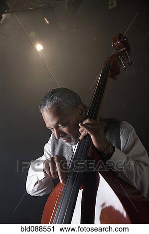 Stock Image - Musician playing double bass on stage. Fotosearch