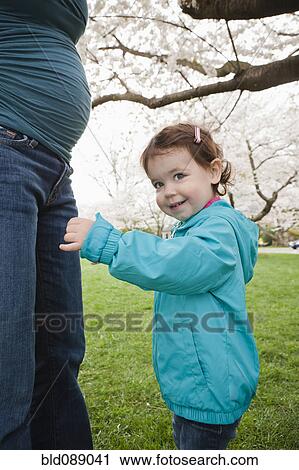 Stock Image - Pregnant Caucasian mother and daughter outdoors. Fotosearch
