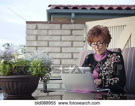 Stock Photography - Senior Caucasian woman using laptop on patio. Fotosearch