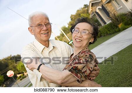 Stock Image - Senior Chinese couple hugging outdoors. Fotosearch