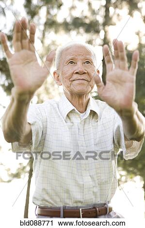 Stock Image - Senior Chinese man doing tai chi outdoors. Fotosearch