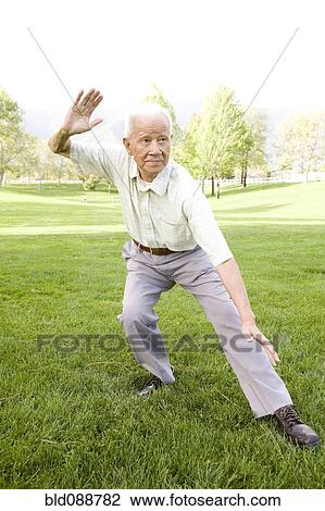 Stock Image - Senior Chinese man doing tai chi outdoors. Fotosearch