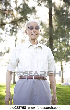 Stock Photo - Senior Chinese man standing outdoors. Fotosearch