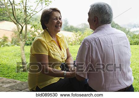 Stock Image - Senior Hispanic couple sitting outdoors together. Fotosearch
