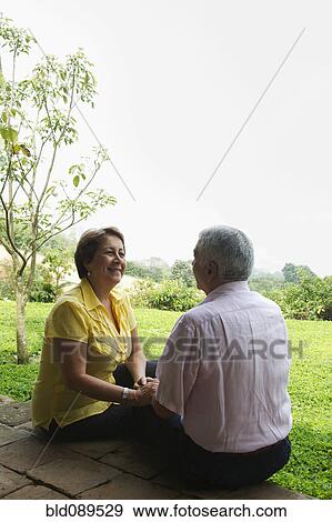Stock Photo - Senior Hispanic couple sitting outdoors together. Fotosearch