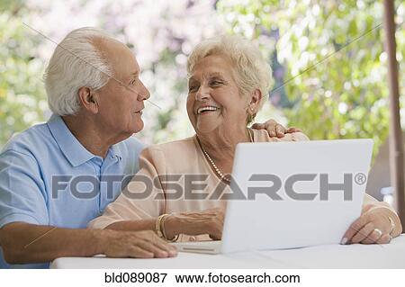 Stock Photo - Senior Hispanic couple using laptop together. Fotosearch