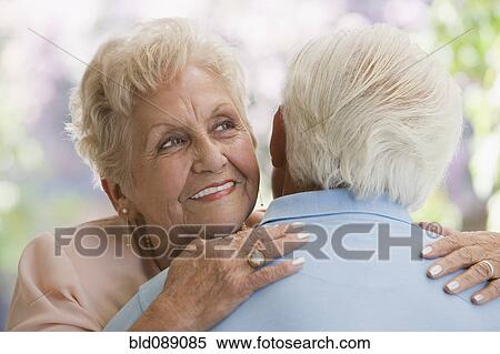 Stock Photography - Senior Hispanic woman hugging husband. Fotosearch