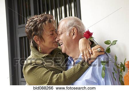 Stock Photograph - Senior Hispanic woman kissing husband. Fotosearch