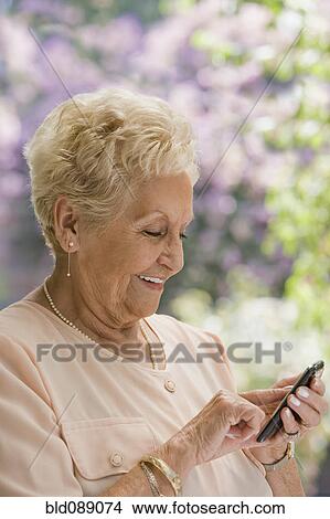 Senior Hispanic woman text messaging on cell phone View Large Photo Image Picture - Senior Hispanic woman text messaging on cell phone. Fotosearch