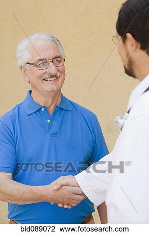Senior man shaking hands with doctor View Large Photo Image Stock Image - Senior man shaking hands with doctor. Fotosearch