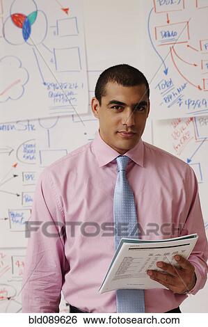 Stock Photograph - Serious businessman standing with paperwork. Fotosearch