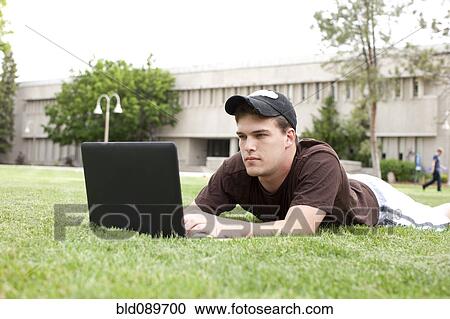 Serious Caucasian man using laptop in grass View Large Photo Image Stock Image - Serious Caucasian man using laptop in grass. Fotosearch