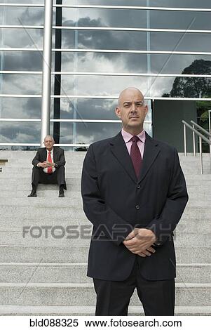 Stock Photography - Serious Hispanic businessman standing outdoors with hands clasped. Fotosearch