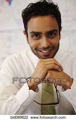 Stock Image - Smiling businessman holding eyeglasses. Fotosearch