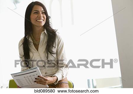 Stock Image - Smiling businesswoman holding paperwork. Fotosearch