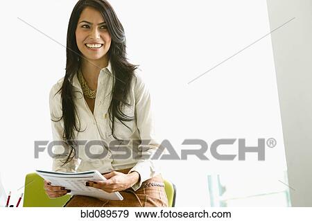 Stock Photo - Smiling businesswoman holding paperwork. Fotosearch