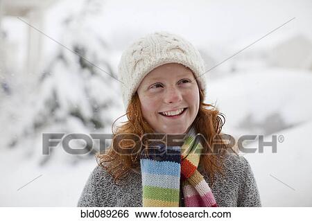 Stock Photograph - Smiling Caucasian girl standing in snow. Fotosearch