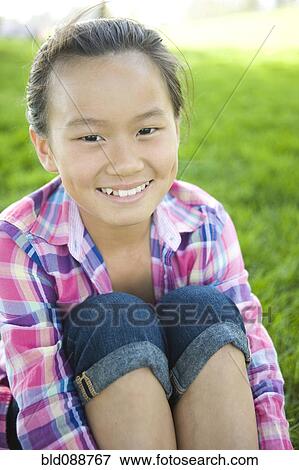Stock Photo - Smiling Chinese girl sitting in grass. Fotosearch