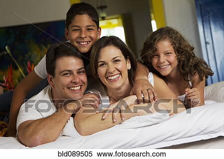 Stock Photography - Smiling family laying on bed together. Fotosearch