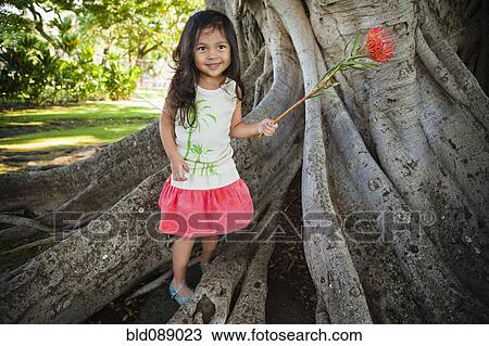 Stock Image - Smiling girl holding exotic flower. Fotosearch