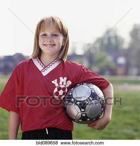 Stock Photo - Smiling girl in uniform holding soccer ball. Fotosearch
