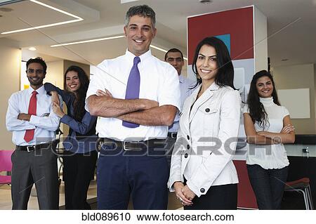Stock Image - Smiling Hispanic business people standing together in office. Fotosearch
